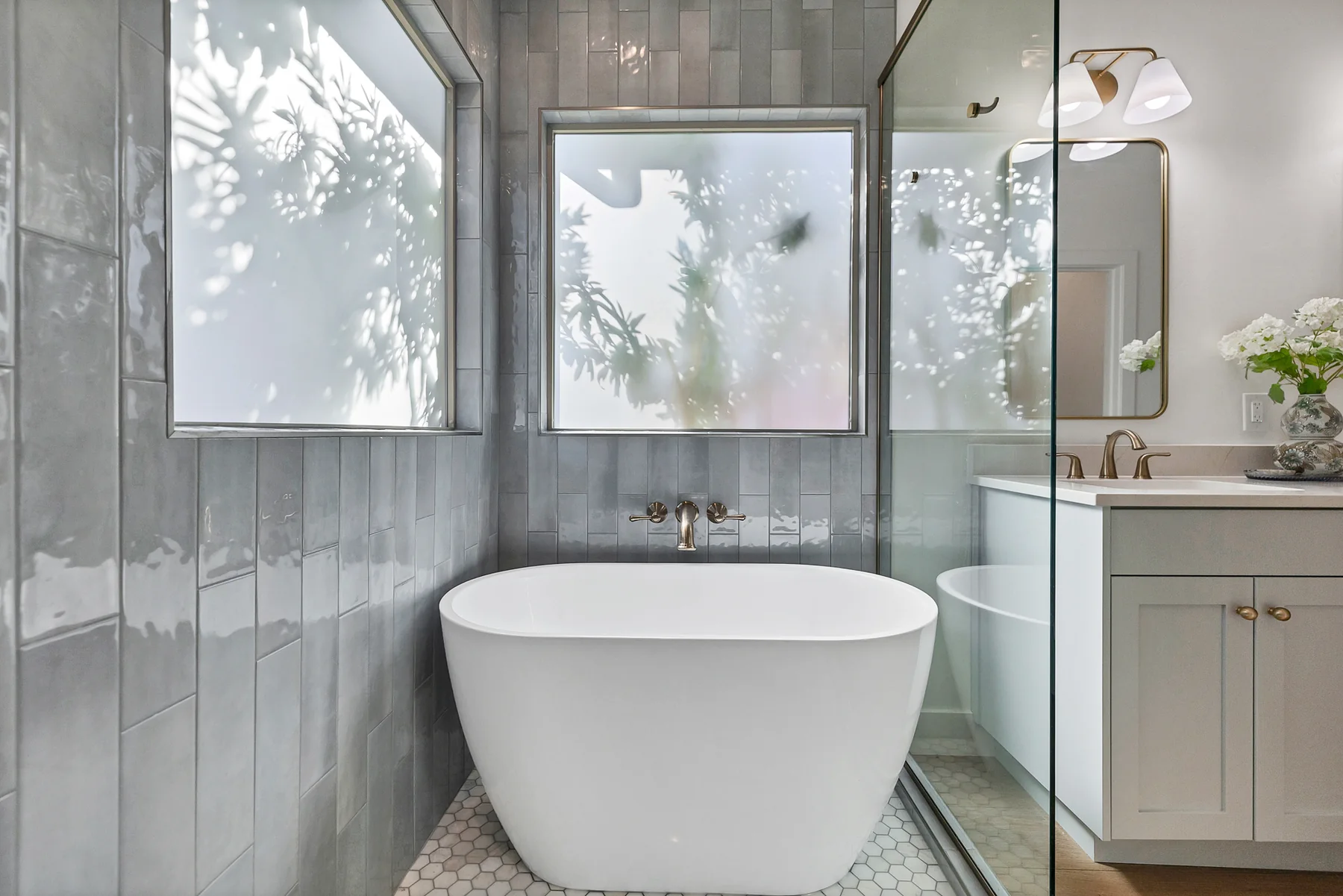 Freestanding tub surrounded by soft blue-gray tile