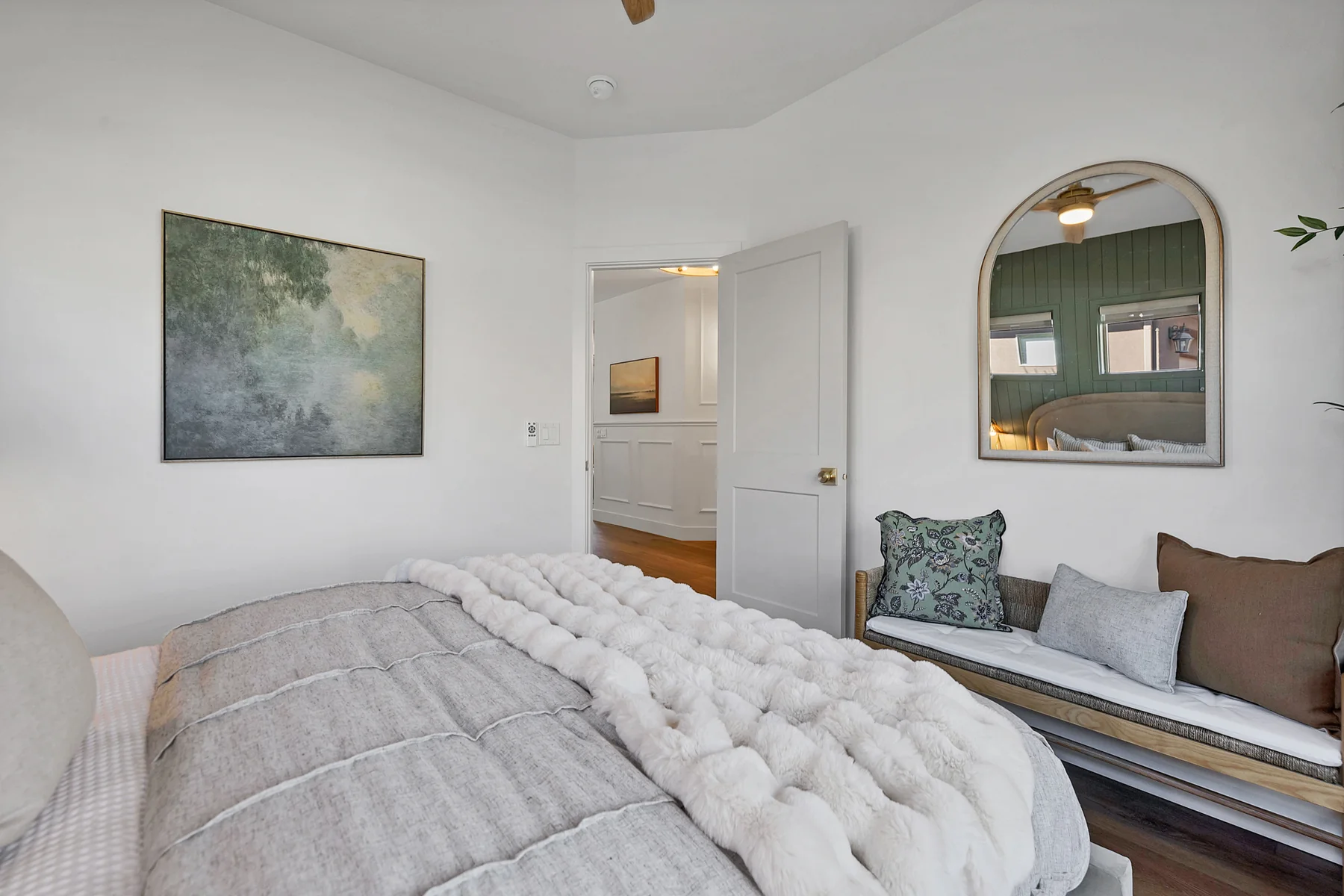 Guest bedroom reverse view with arched mirror and window seat