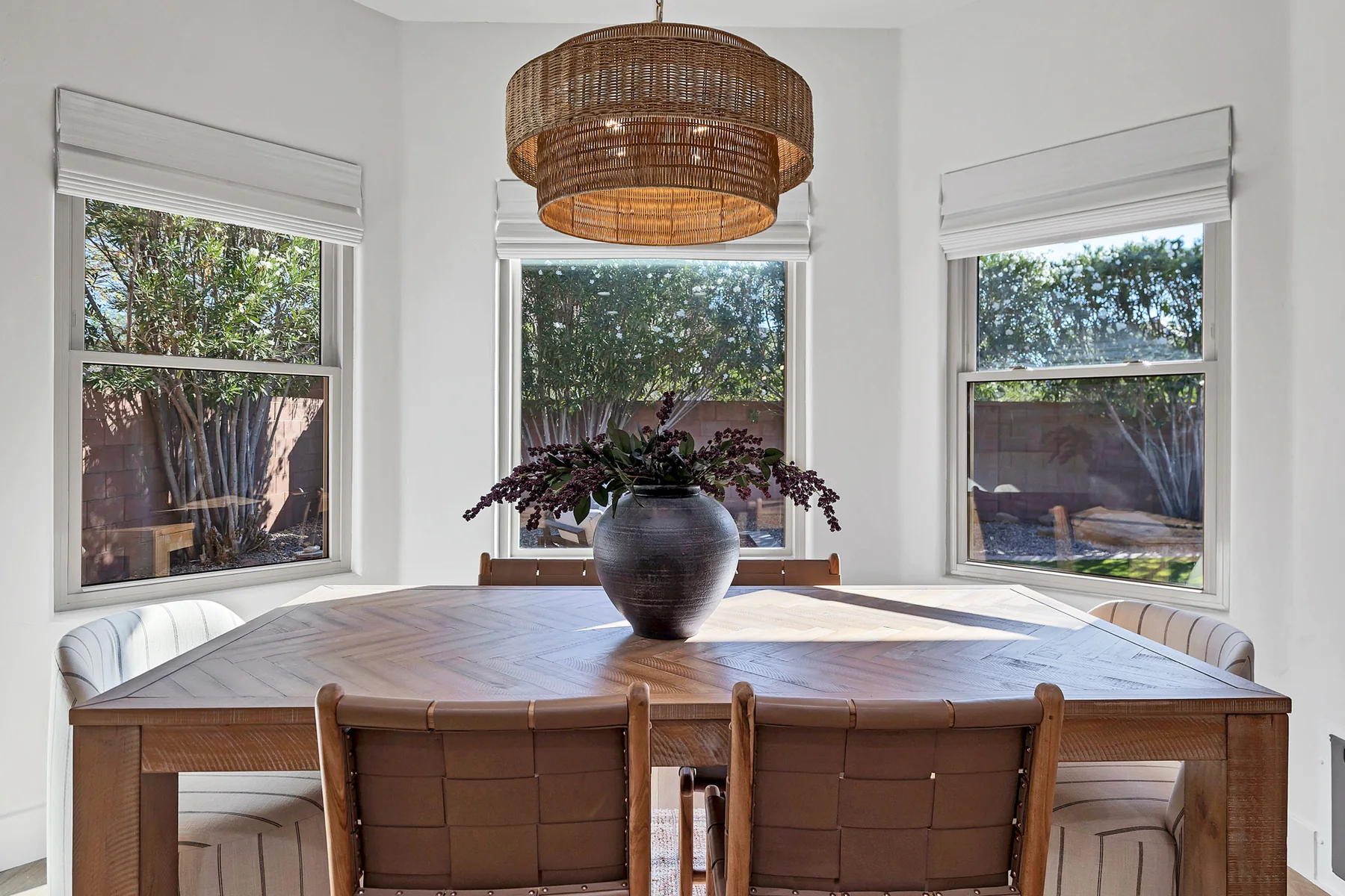 Round wood dining table under a woven pendant