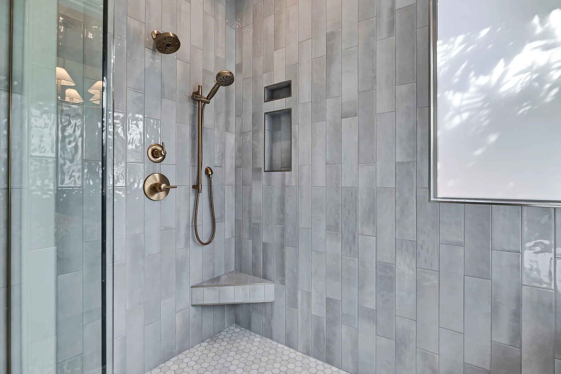 Primary shower with blue-gray tile and brass fixtures